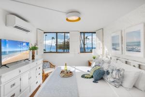 a living room with a white bed and a view of the ocean at Kanai A Nalu 211 in Wailuku