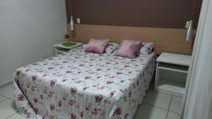 a bedroom with a bed with pink pillows on it at Aconchegante Flat no Aldeia das Águas in Barra do Piraí