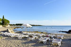 a group of lounge chairs and an umbrella on a beach at Apartments with a parking space Zambratija, Umag - 7059 in Zambratija