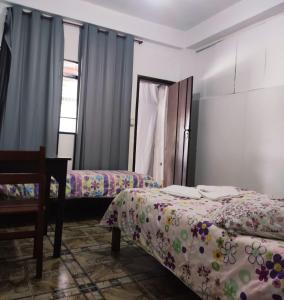 Habitación con 2 camas, silla y ventanas. en Pousada Estrada de Ferro en Tiradentes