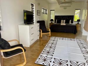 a living room with a bed and a tv and a rug at Rarotonga Villas Absolute Beachfront in Arorangi