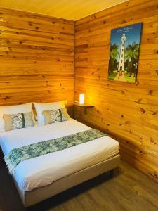 ein Schlafzimmer mit einem Bett in einem Zimmer mit Holzwänden in der Unterkunft Bungalow KURA in Moorea