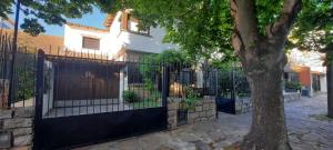 a house with a black fence and a tree at Chalet Playa Grande in Mar del Plata