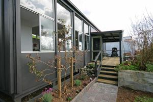 a house with glass walls and a porch with flowers at Bella Park - New Plymouth Holiday Studio in New Plymouth