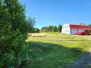 a large field with a barn and a red truck at cozy apartment near the ocean in Guysborough