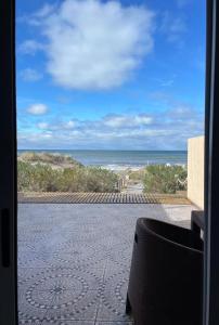 - une vue sur l'océan depuis la terrasse pourvue d'une chaise dans l'établissement Las Piedritas Casa de Mar Loft, à Las Grutas