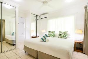 - une chambre avec un grand lit blanc et un miroir dans l'établissement 27 Central Plaza, à Port Douglas