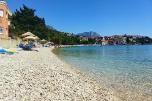 einen Strand mit Stühlen und Sonnenschirmen neben dem Wasser in der Unterkunft Apartments by the sea Podaca, Makarska - 15685 in Podaca