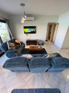uma sala de estar com um sofá azul e uma televisão em Ground chlat first row lagoon 2 bedrooms at Blanca marassi em El Alamein