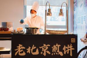 a chef is preparing food in a kitchen at Beijing Marriott Hotel Northeast in Beijing