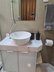 a bathroom with a white sink and a mirror at Cobertura Duplex com Piscina Exclusiva na Pituba! in Salvador