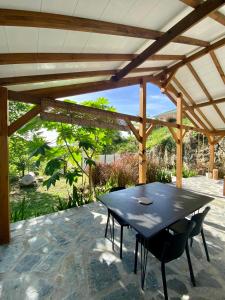 a black table and chairs under a wooden pergola at Villa Kara in Grand-Bourg