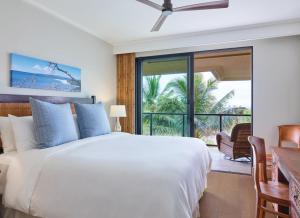 a bedroom with a large white bed and a balcony at Timbers Kaua'i in Lihue