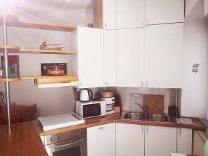 a kitchen with white cabinets and a sink and a microwave at Residenza Esse in Angera