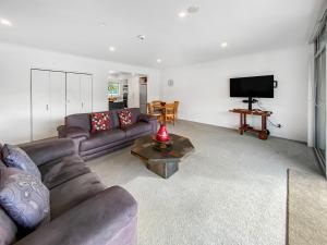 a living room with a couch and a television at Oxley's Waterfront Apartment in Picton