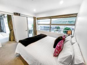 um quarto com uma cama branca com almofadas e uma janela em Oxley's Waterfront Apartment em Picton