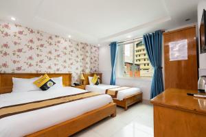 a bedroom with two beds and a desk and a window at Janus Hotel 168 in Ho Chi Minh City