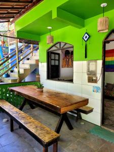 eine grüne Wand mit einem Holztisch und einer Bank in der Unterkunft Jurema Hostel in Itacaré