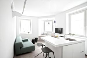 a white kitchen with a sink and a chair at Studio Emmi in Ljubljana