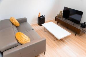 a living room with a gray couch and a tv at Bienvenue chez vous! in Pointe-Calumet