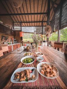 a wooden table with plates of food on it at Jungle Haven Bali - Eco Lodge in Meliling