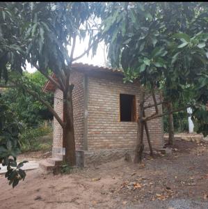 a small brick house with a window in a yard at Cantinho HAKUNA MATATA-Vale do Capão a 5 min da Vila in Vale do Capao