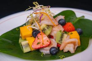 a plate of food with fruit on a green leaf at Hilton Haikou Meilan in Haikou
