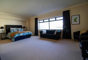 um quarto com uma cama, uma cadeira e uma janela em Large luxury apartment located right in town em Taupo