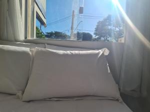 uma almofada sentada numa cama em frente a uma janela em Apt 17 com 2 suítes com ar cond em Montes Claros