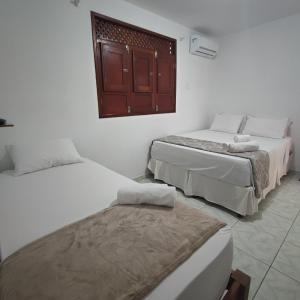 a room with two beds and a window at Pousada Sunshine Patacho - Praia do Patacho - Rota Ecológica dos Milagres, Porto de Pedras in Pôrto de Pedras
