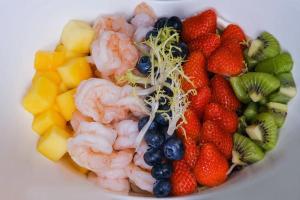 a bowl of fruit with shrimp strawberries kiwis andrants at Hilton Haikou Meilan in Haikou