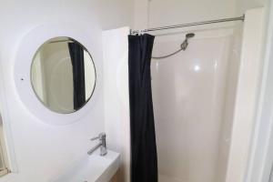 bagno con tenda da doccia nera e specchio di Cedric Cottage a Mallacoota