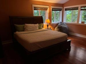 a bedroom with a bed and a lamp and windows at Serene Oasis Getaway with Sauna and a swim spa. in Portland