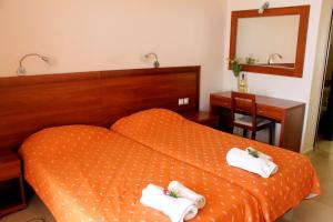 a bedroom with an orange bed with towels on it at Lido Sofia Apartments in Agios Gordios