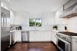 uma cozinha com armários brancos e electrodomésticos de aço inoxidável em Villa Palma-Hollywood Beach - Summer Getaway! em Hollywood