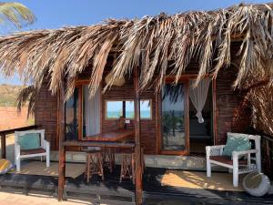 Cabaña con techo de paja, sillas y mesa en Palo Santo Sanctuary, en Canoas de Punta Sal