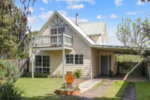 a white house with a porch and a fence at Cape Cottage in Cape Woolamai