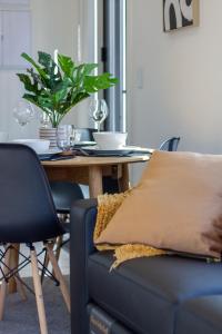 a dining room table with a couch and a table with a plant at Avon Haven City Escape - 1 bed 1 bath in Christchurch +25 photos