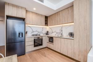 a kitchen with wooden cabinets and a stainless steel refrigerator at Golden Horizons - Resort Living in the Clouds in Gold Coast