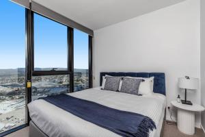 a bedroom with a large bed and large windows at Golden Horizons - Resort Living in the Clouds in Gold Coast