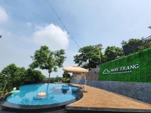 a swimming pool with an umbrella in front of a sign at Mây Trắng Farmstay Villas Venuestay in Ba Vì