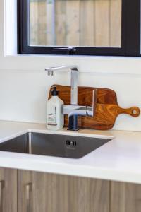 a sink with a bottle of soap and a wooden holder at Avon Haven City Escape - 1 bed 1 bath in Christchurch