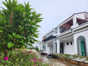 a house in the rain with a tree and flowers at Mây Trắng Farmstay Villas Venuestay in Ba Vì