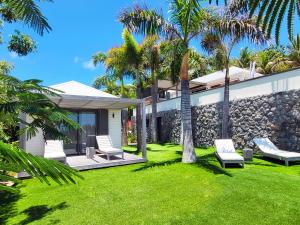 a yard with chairs and palm trees in front of a house at Villa Coco Rock in Saint Barthelemy