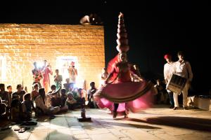 um grupo de pessoas assistindo um artista em um palco em Mala Ki Dhani em Jaisalmer