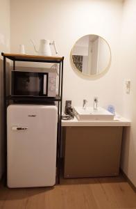 a microwave on top of a refrigerator next to a sink at MARUKOU HOTEL in Tokyo