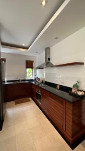 uma cozinha com armários de madeira e um balcão preto em The Residence Resort & Spa Retreat em Praia de Bang Tao
