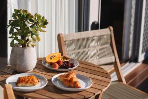 a wooden table with three plates of croissants and fruit at Pippi Beach Loft in Yamba