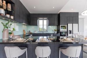 a kitchen with a large island with white chairs at Big & Stylish 5 Bed 4 Bath Private Garden Pool Villa at Thongson Bay Beach in Koh Samui 