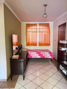 Habitación con cama rosa y ventana en Pousada Lopes na Fama en Goiânia